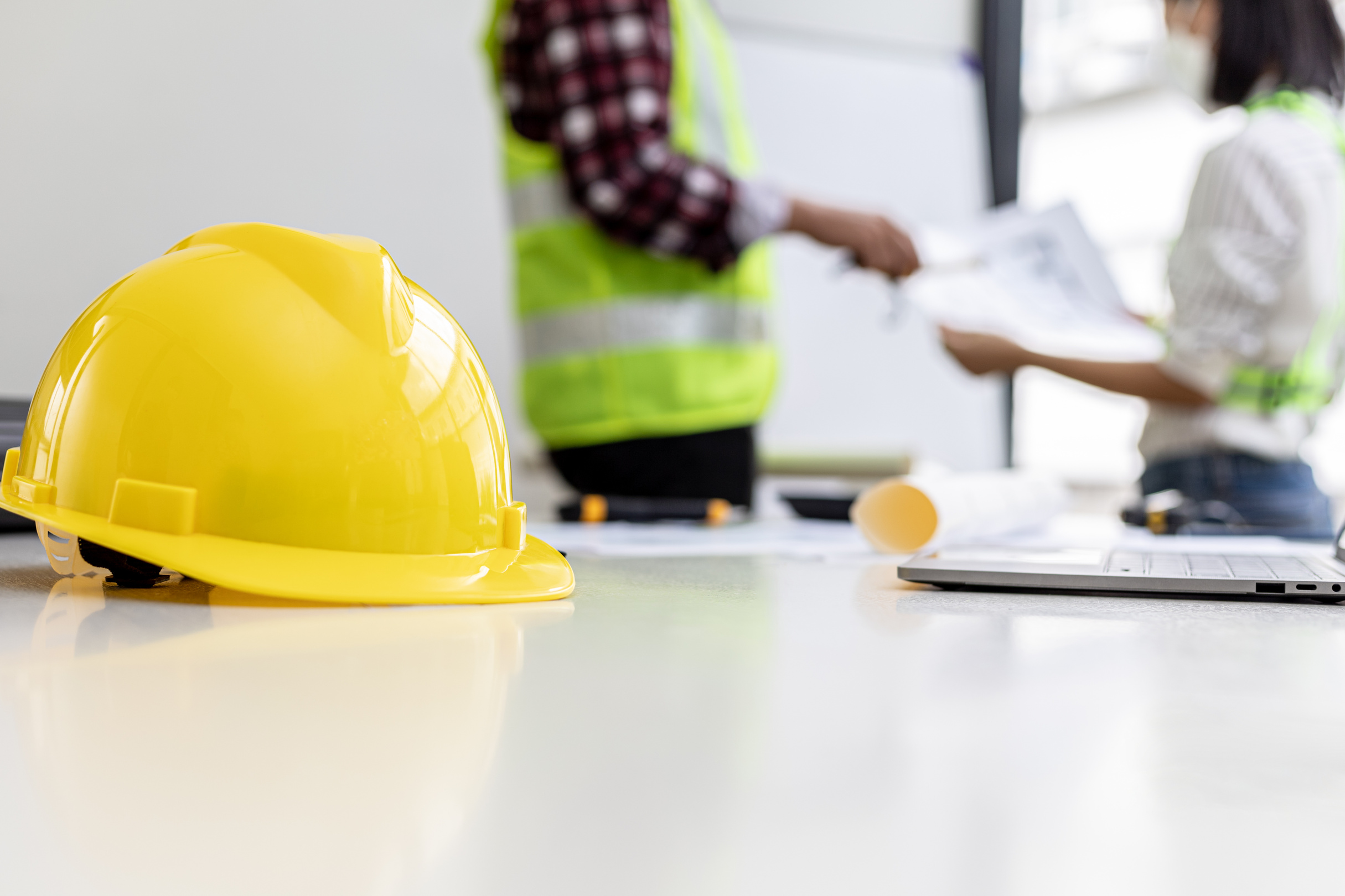 Close-up engineers' yellow safety helmets placed in a meeting room of engineers and architects, where they have a construction planning meeting and a revision. Construction and interior concepts.